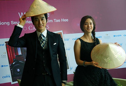 Nam diễn viên Song Seung Hun và nữ diễn viên Kim Tae Hee tươi cười trong chiếc nón lá của fan tặng trong chuyến thăm Việt Nam hồi tháng 1/2012 để quảng bá cho bộ phim My Princess.